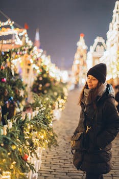 一位穿着冬装的妇女在户外圣诞市场微笑着享受节日灯光