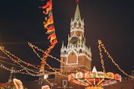 克里姆林宫塔楼在充满活力的夜市上，被节日灯光和装饰品笼罩着