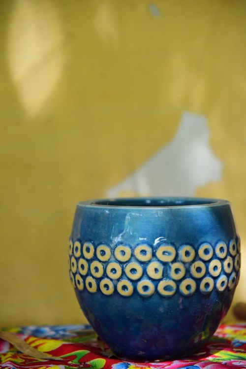 Free A vibrant blue ceramic pot adorned with yellow circular designs against a colorful backdrop. Stock Photo