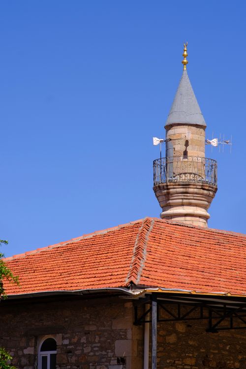 Free Charming historic minaret set against a vibrant blue sky in Foça, İzmir. Stock Photo