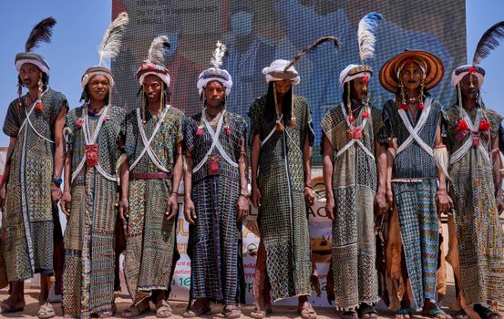 Men participating in a traditional festival in Agadez, Niger, wearing colorful attire and headpieces.