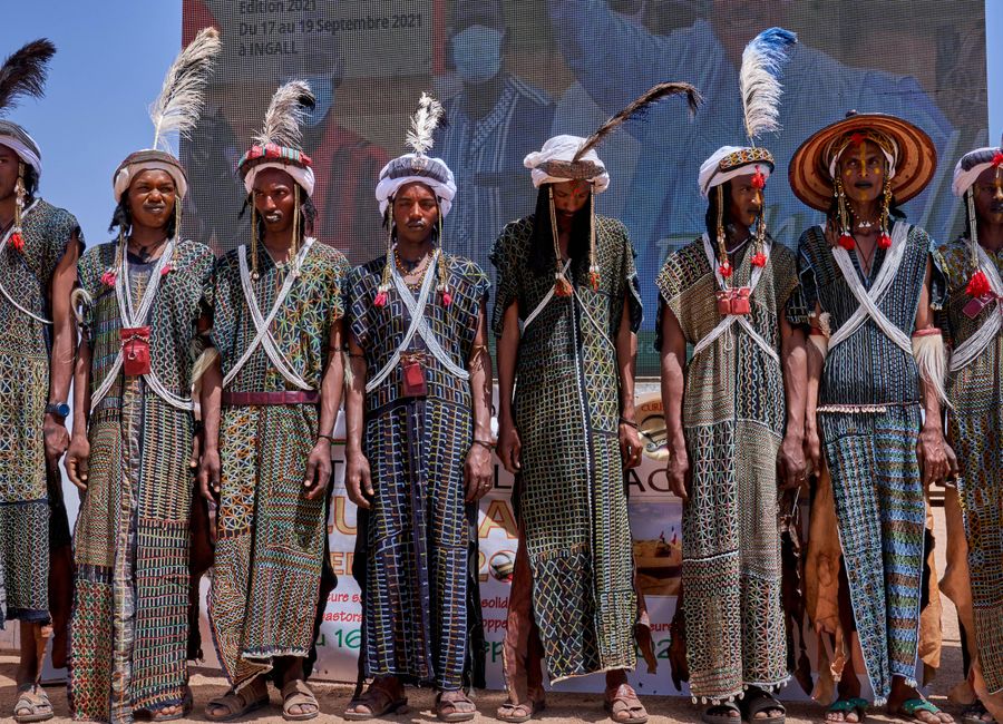 Men participating in a traditional festival in Agadez, Niger, wearing colorful attire and headpieces.