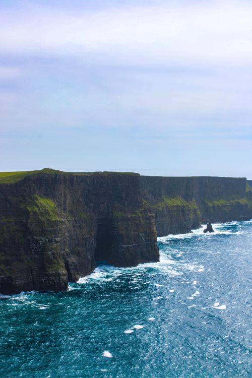 Free Breathtaking view of the Cliffs of Moher, Ireland with waves crashing below. Ideal for travel and nature enthusiasts. Stock Photo