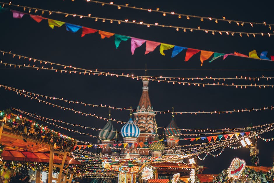 Strings of illuminated garlands hanging over holiday market on background of majestic cathedral