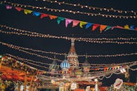 在雄伟的大教堂背景下，一串发光的花环悬挂在假日市场的上空