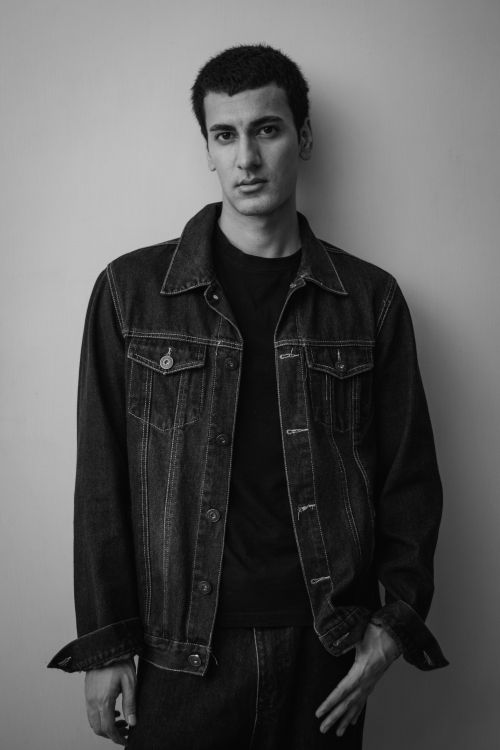 Free Stylish black and white portrait of a young man wearing a denim jacket indoors. Stock Photo