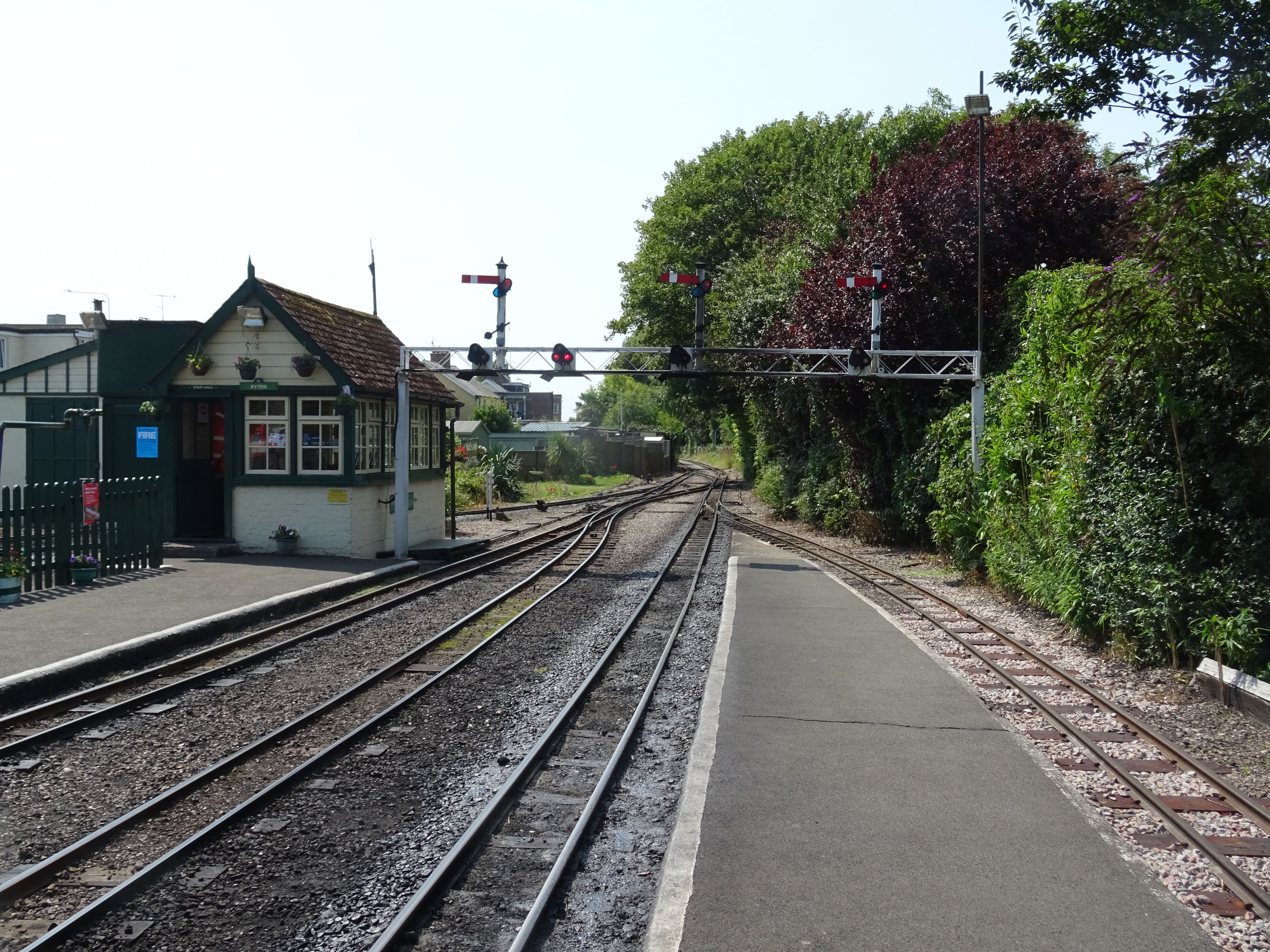 A scenic view of a narrow-gauge railway platform in Hythe, England, during summer.
