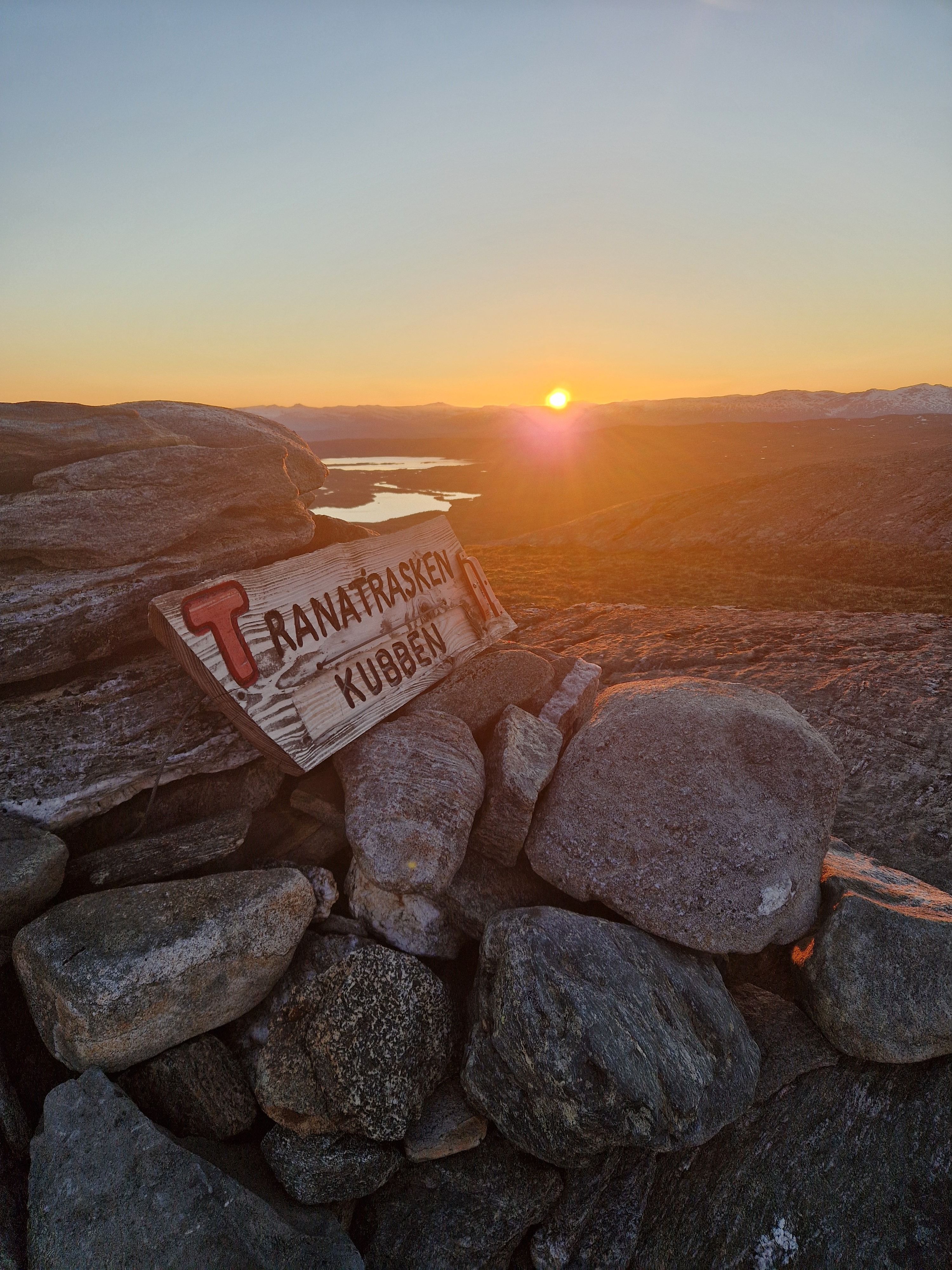 Scenic sunset view over rocky landscape with directional signage to Tranatrask and Kubben.