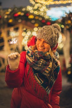 在节日的户外庆祝活动中，一位身穿冬装的女子手持烟花，面带微笑