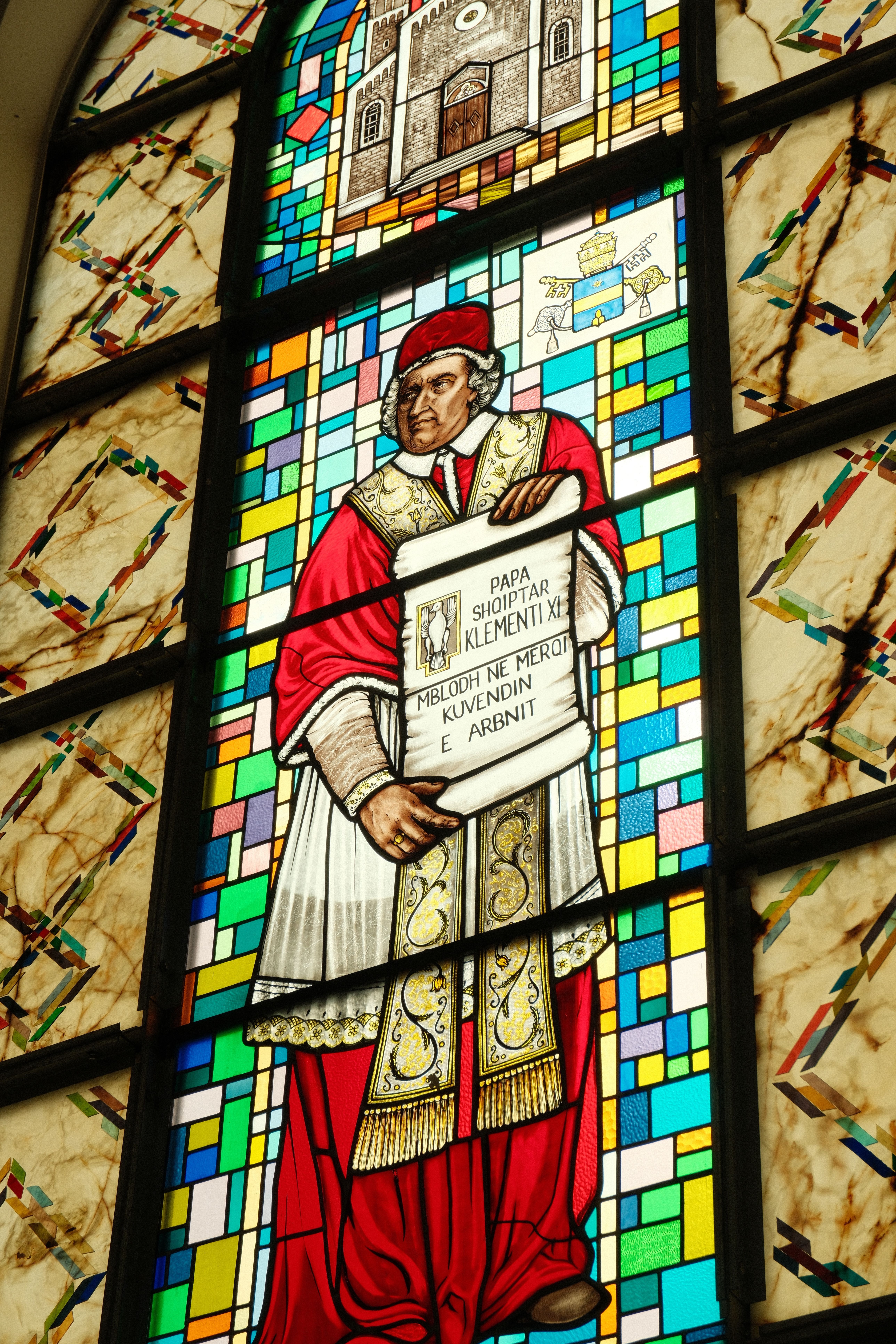 Colorful stained glass depicting a historical figure in traditional clerical attire located in Priştine.