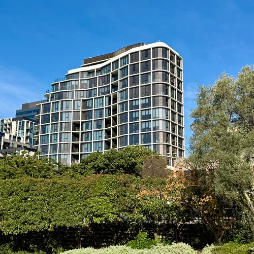 Free Contemporary apartment building with glass facade surrounded by lush greenery in Box Hill. Stock Photo