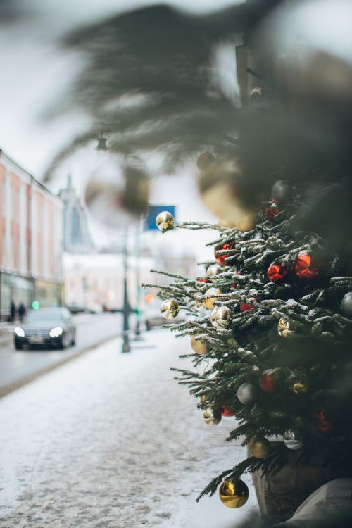 Free Festive Christmas tree adorned with ornaments on a snowy street in winter. Stock Photo