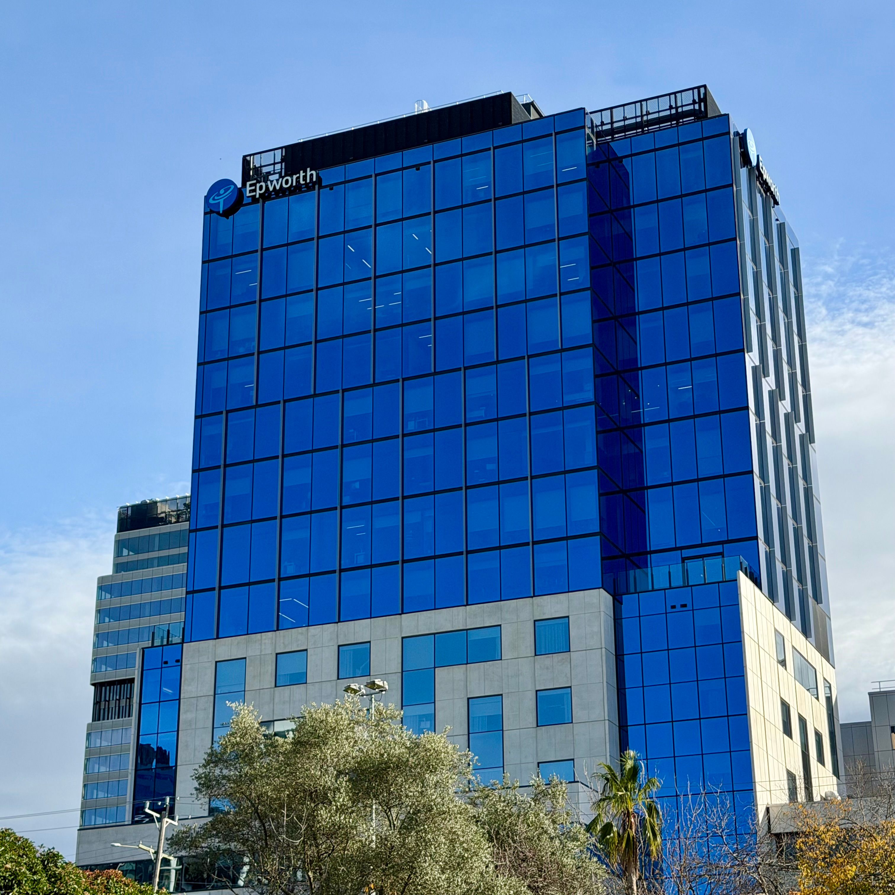 A striking high-rise with blue glass facade in Box Hill, Victoria, on a clear day.