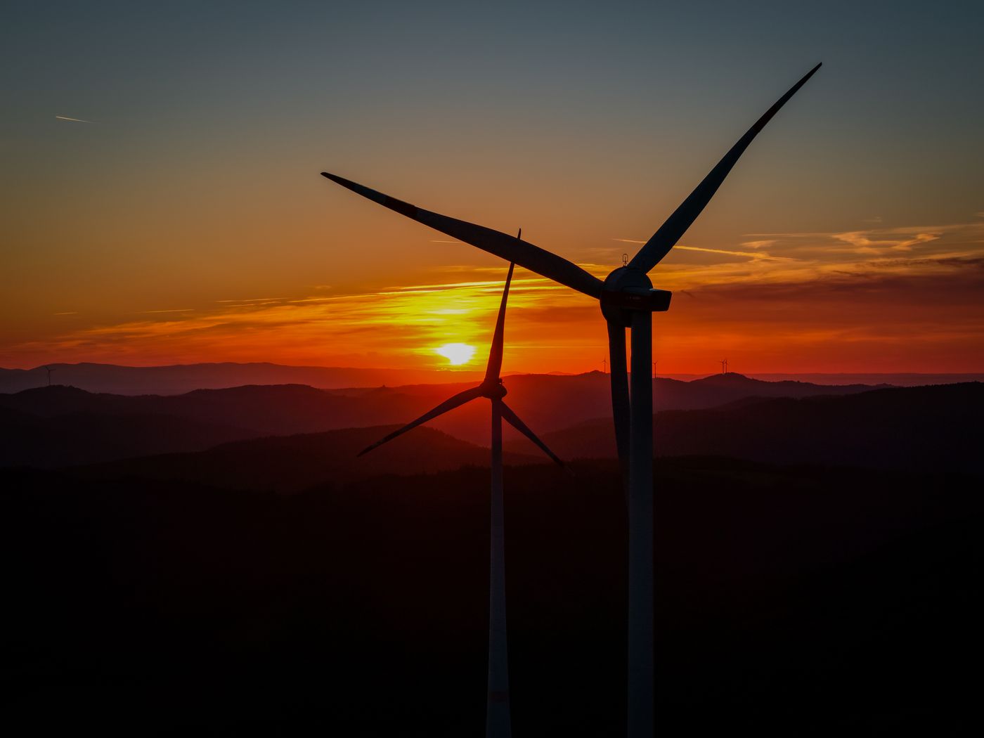 Silhouetted wind turbines at sunset in Villingen-Schwenningen, Germany, emphasizing renewable energy.