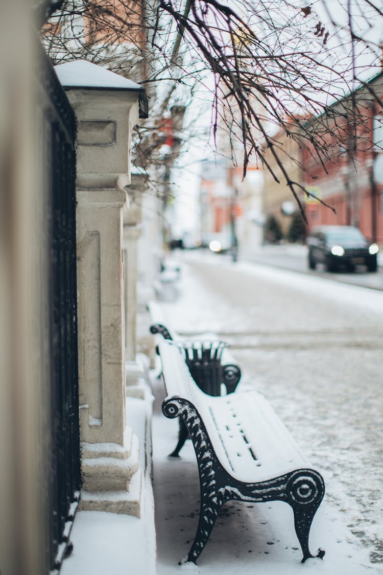 Snow Covered Bench On Sidewalk