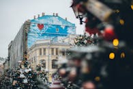 城市广场上，旧建筑立面带有创意涂鸦和铭文，圣诞树上装饰着装饰品和彩色小玩意