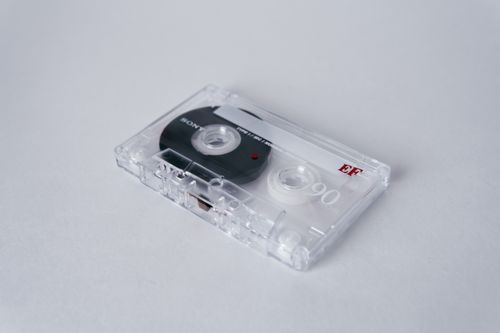 Free Close-up of a vintage cassette tape with clear casing on a white background, highlighting audio nostalgia. Stock Photo
