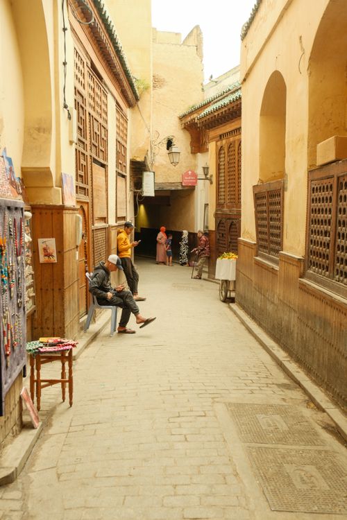 Free Charming alleyway with people in Fes, Morocco, showcasing traditional architecture and daily life. Stock Photo