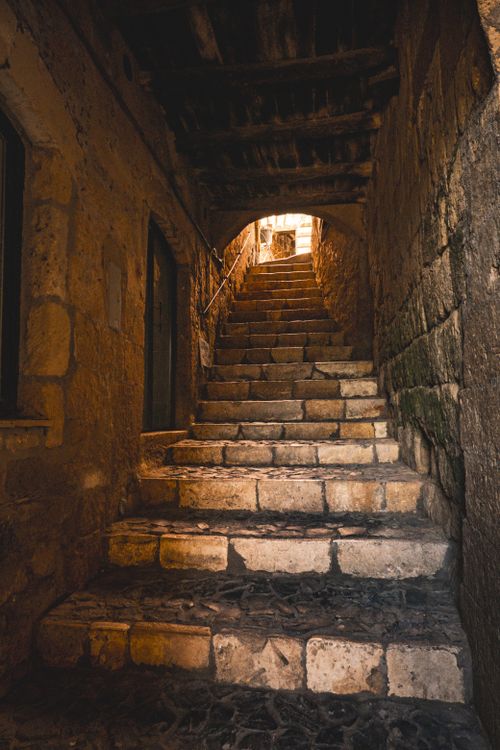 Free Cozy historic stone staircase leading through a dimly lit old alleyway. Stock Photo