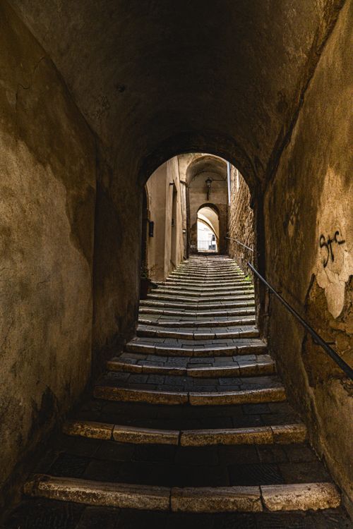 Free A scenic view of an ancient stone stairway through a dark archway, leading to daylight. Stock Photo