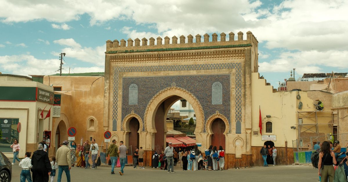 Visitors at the iconic Bab Bou Jeloud in Fes, Morocco, enjoying a sunny day.