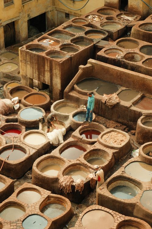 Free Aerial view of workers in a traditional tannery in Fes, Morocco, showcasing vibrant dye pits in a historic setting. Stock Photo