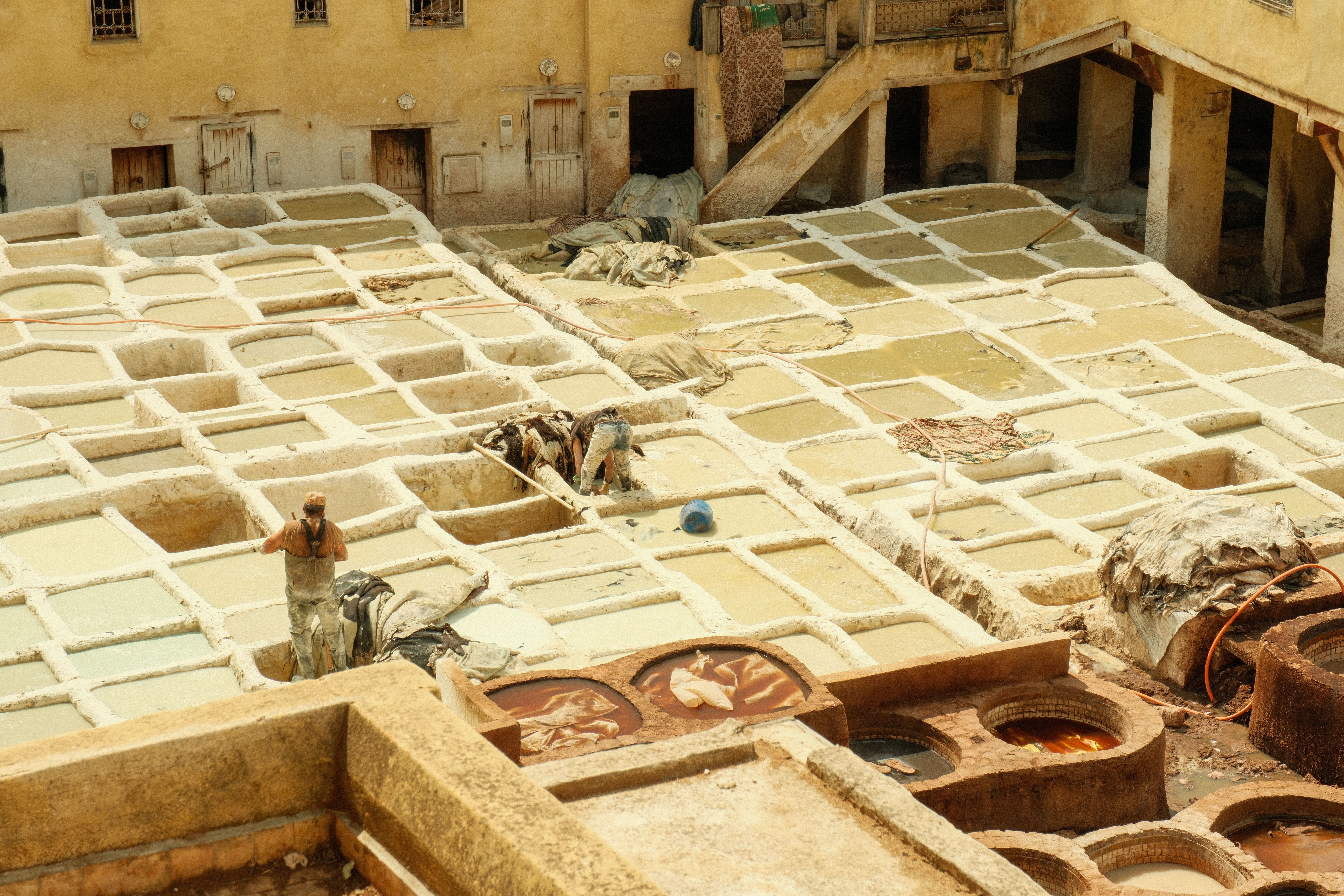 Aerial view of workers at the historic leather tannery in Fes, Morocco, showcasing ancient techniques.