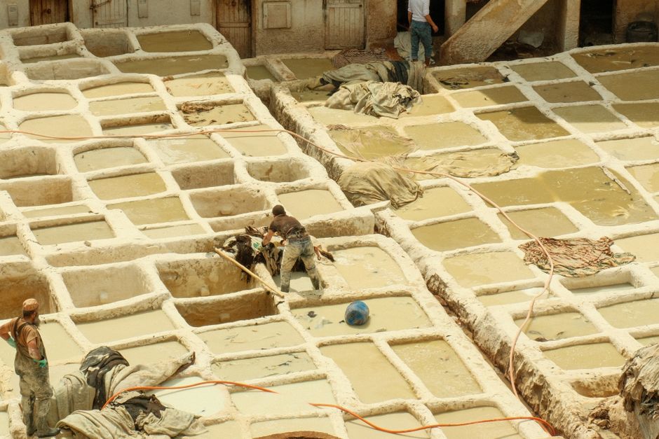 View of traditional leather tannery in Fes, Morocco, showcasing workers at ancient vats.