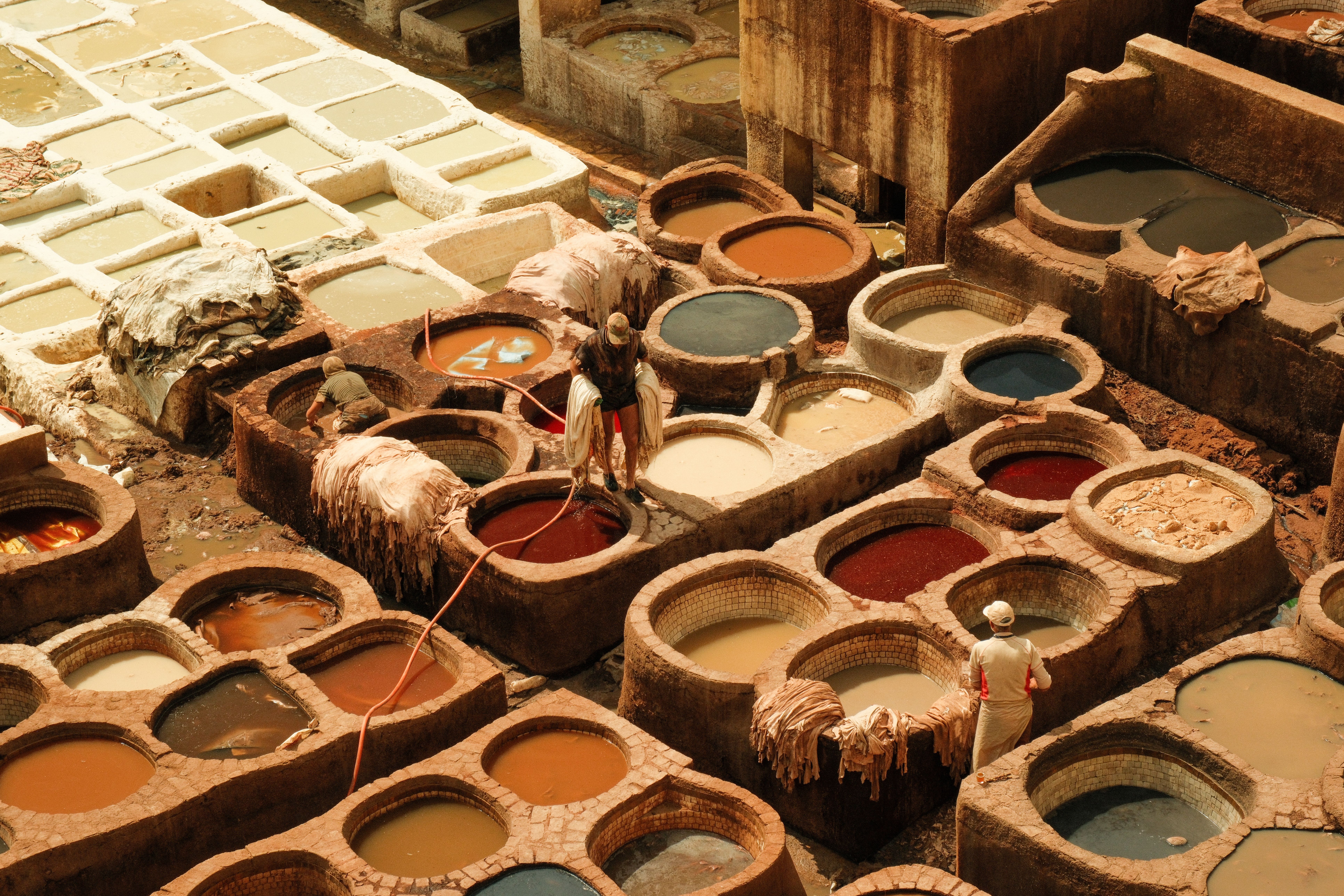 Overhead view of Fes tannery with workers and colorful dye vats, Morocco.
