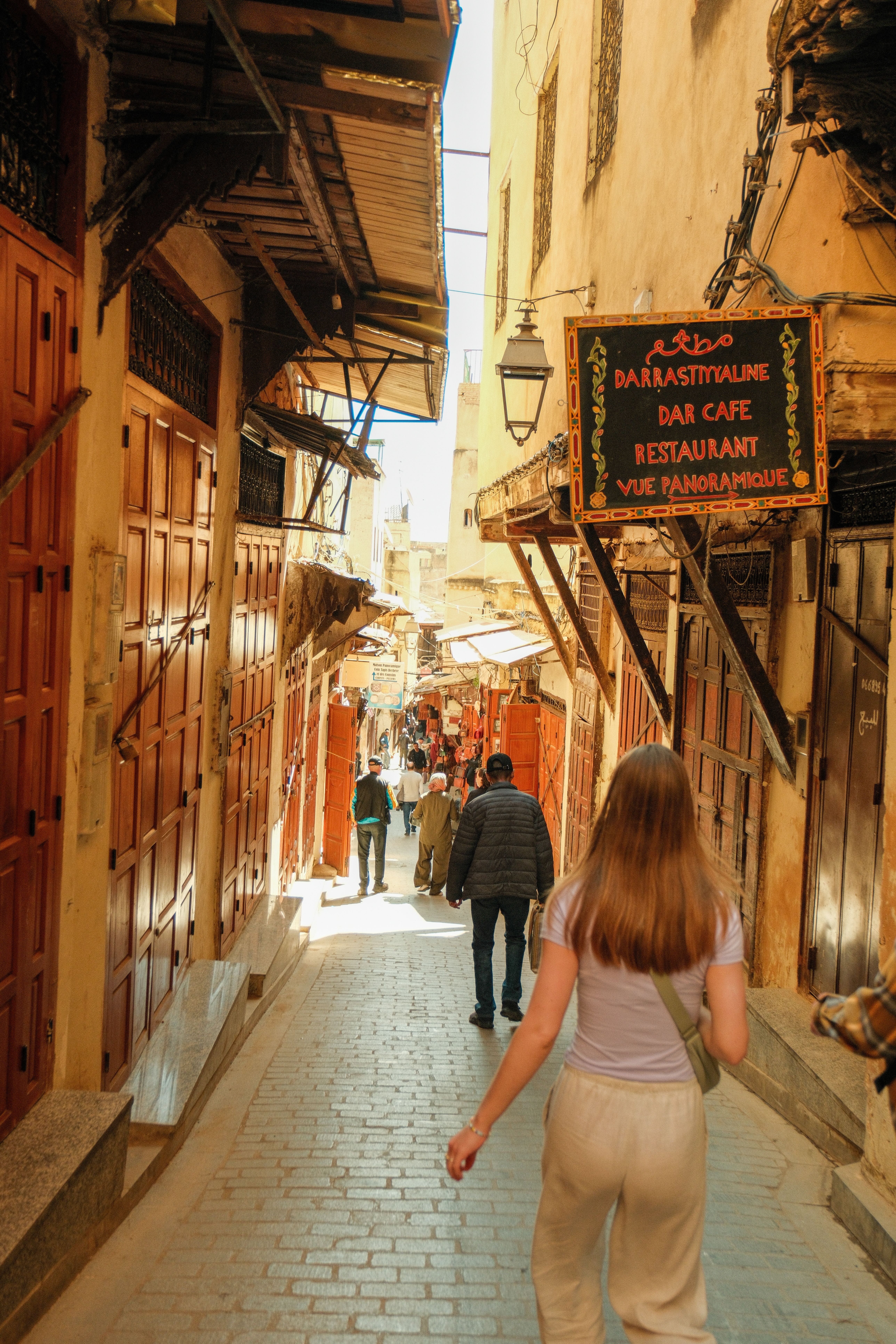 Tourists walk through the narrow streets of Fes, Morocco, capturing the vibrant atmosphere of the Medina.