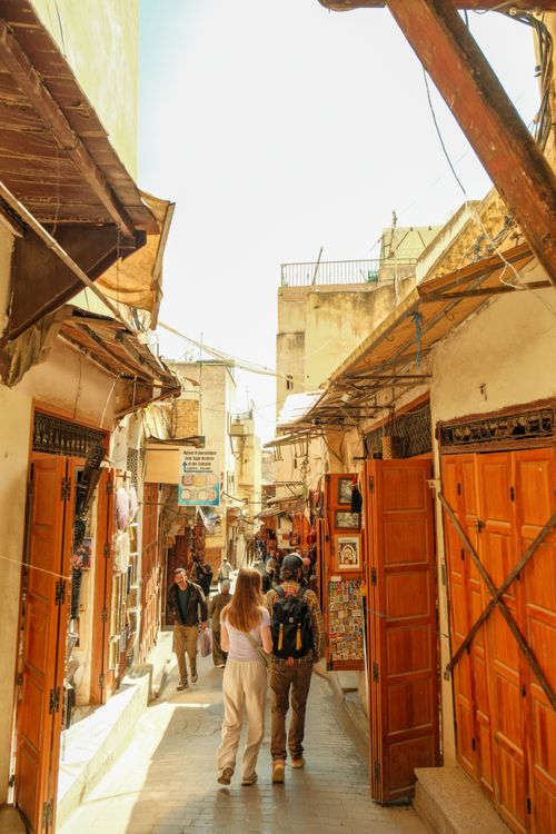 Free Tourists explore the bustling alleys of Fes Medina, showcasing traditional Moroccan architecture. Stock Photo