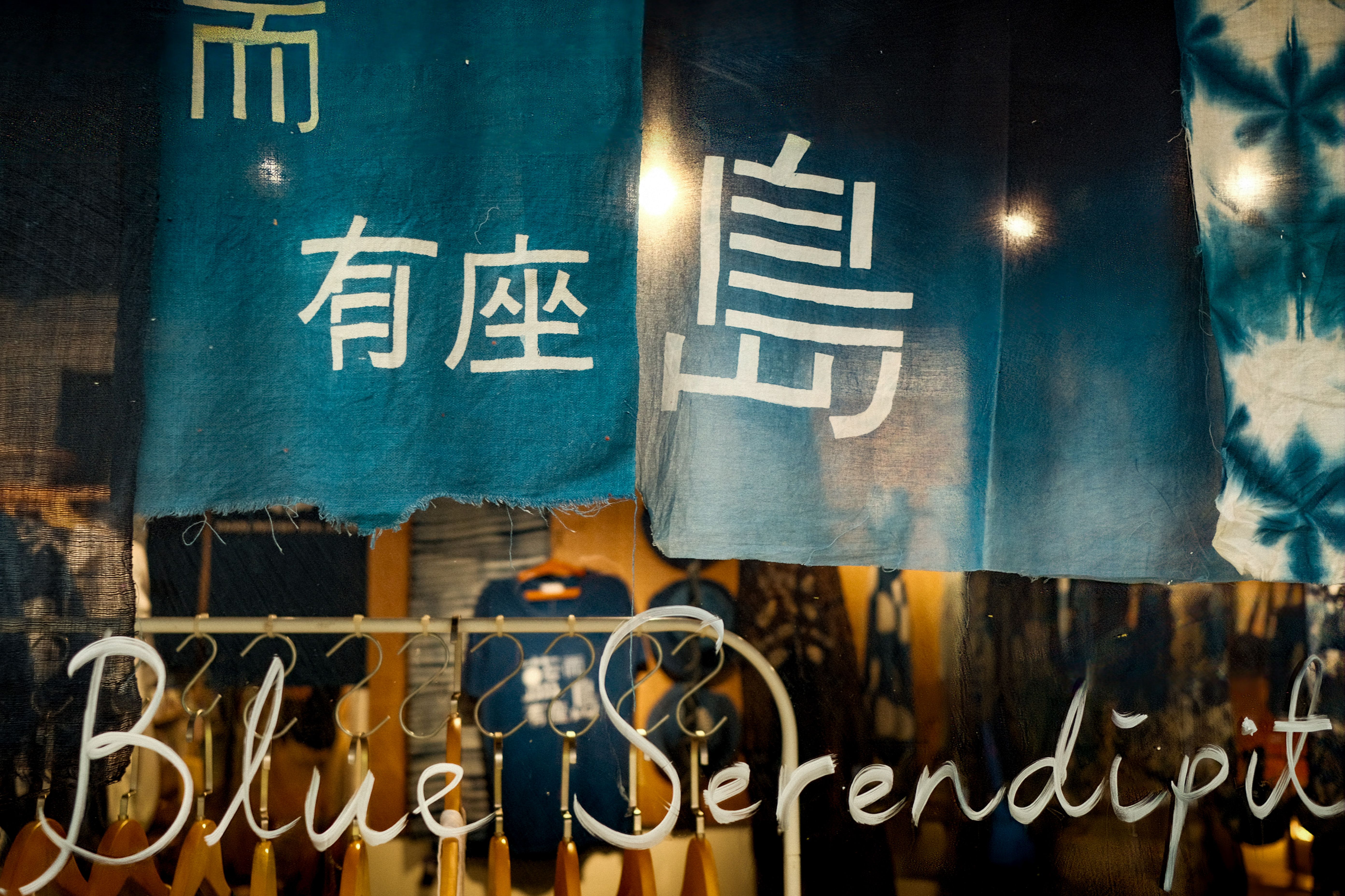 The Midwest Girl storefront at dusk with the painted sign glowing under a streaked indigo sky