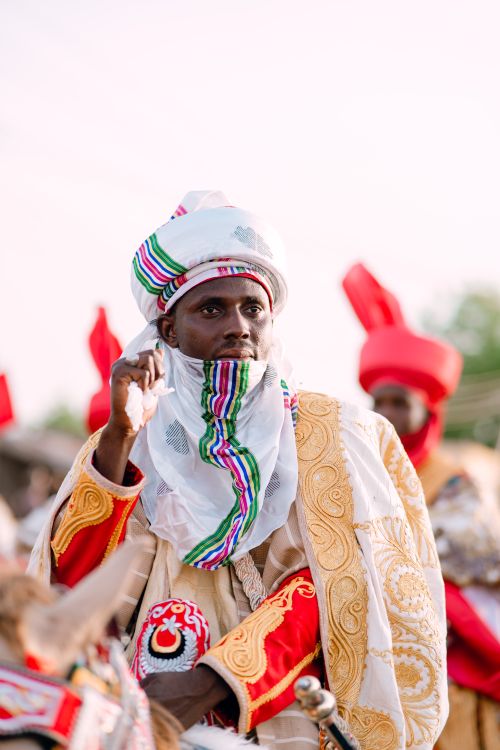Free Person wearing colorful traditional Nigerian clothing during a cultural festival with vibrant background. Stock Photo