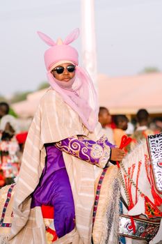 A vibrant portrait of a traditionally dressed horseman in a cultural parade, showcasing rich fabrics and ornate details.