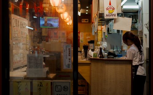 Free Warmly lit view inside an Osaka restaurant featuring a staff member preparing for the night. Stock Photo