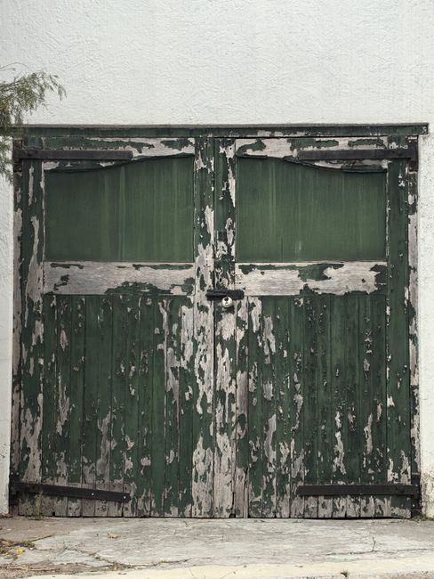 A rustic, weathered green door with peeling paint in Cape Town, South Africa.