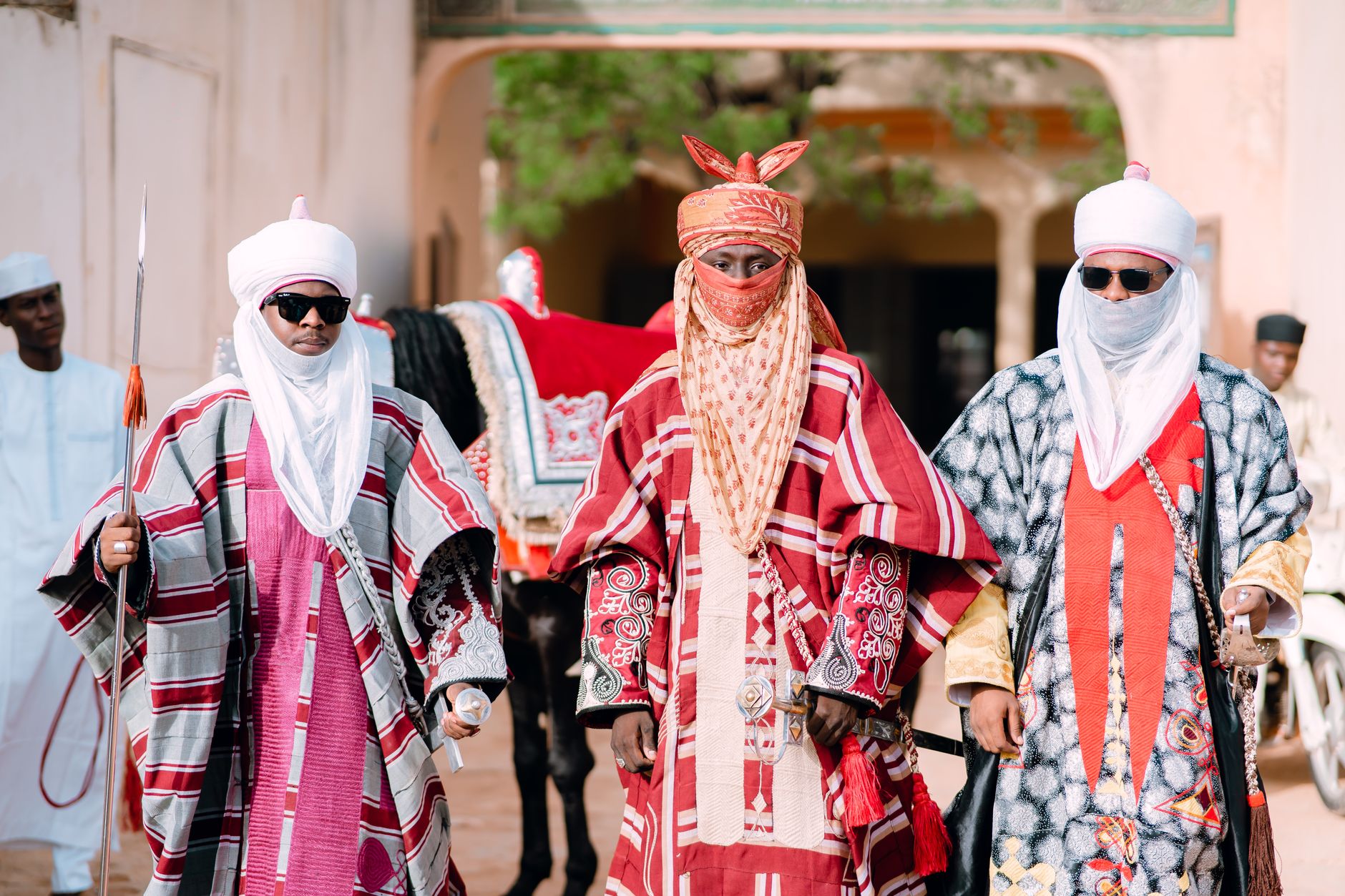 Three men in vibrant traditional attire symbolize African cultural heritage and royalty.