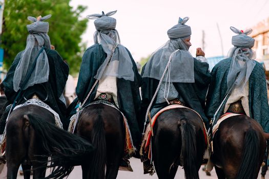 Group of horseback riders in traditional clothing participating in a cultural parade.