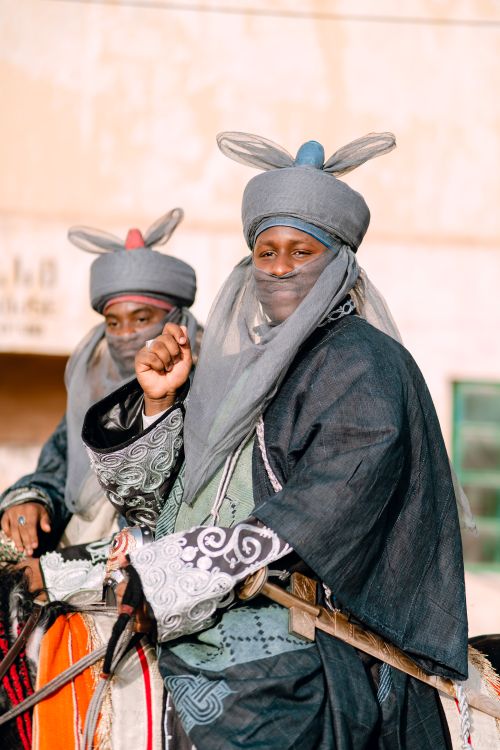 Free Two men in traditional costumes on horses in a parade or festival setting. Stock Photo