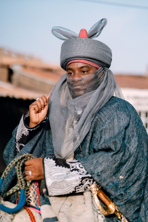 Free A man dressed in traditional African attire with ornate patterns rides outdoors. Captured in vivid daylight. Stock Photo