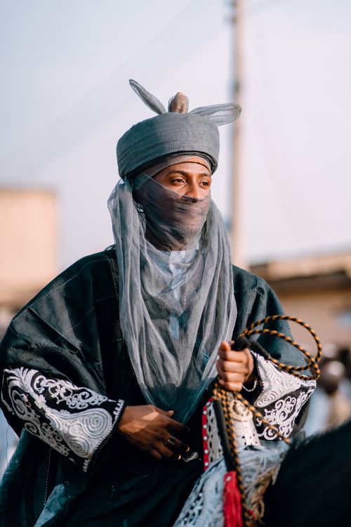 Free A man in traditional cultural attire riding a horse, showcasing rich patterns and colors. Stock Photo