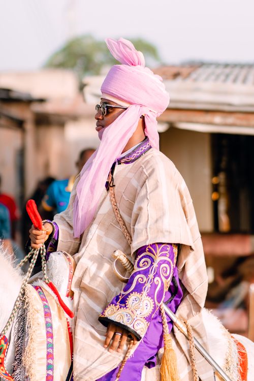 Free A person dressed in vibrant traditional clothing riding a horse during a cultural festival outdoors. Stock Photo