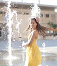 女人在喷泉旁享受阳光明媚的一天，顽皮地微笑着