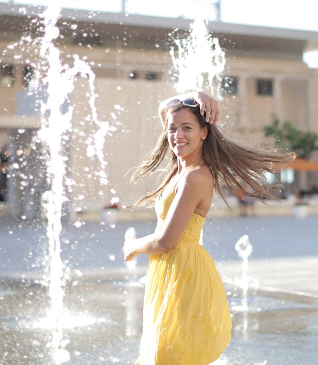 Free Woman in Yellow Dress Standing Near Water Fountain Stock Photo