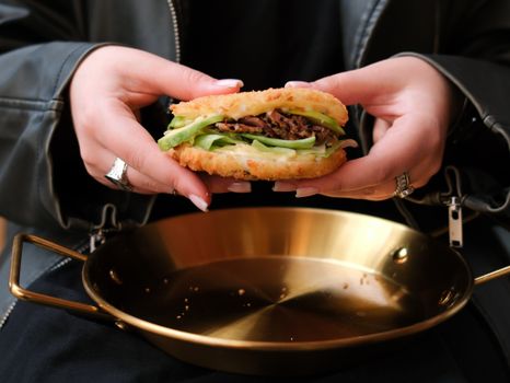A close-up of hands holding a unique rice sandwich over a golden platter. Perfect for food photography.