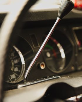 Detailed view of a vintage car dashboard with a silver gear shift, showcasing classic design.