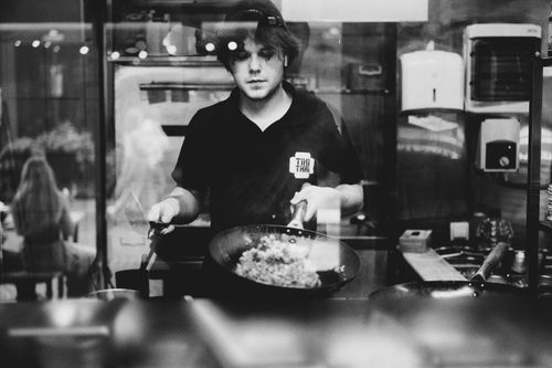 Free Black and white photo of a chef preparing food in a kitchen behind glass in Lviv, Ukraine. Stock Photo