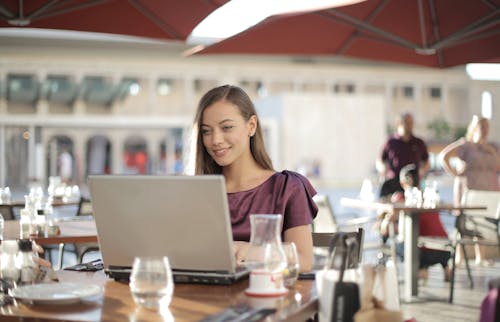 Free Woman in Purple Shirt Sitting by the Table Using Macbook Stock Photo