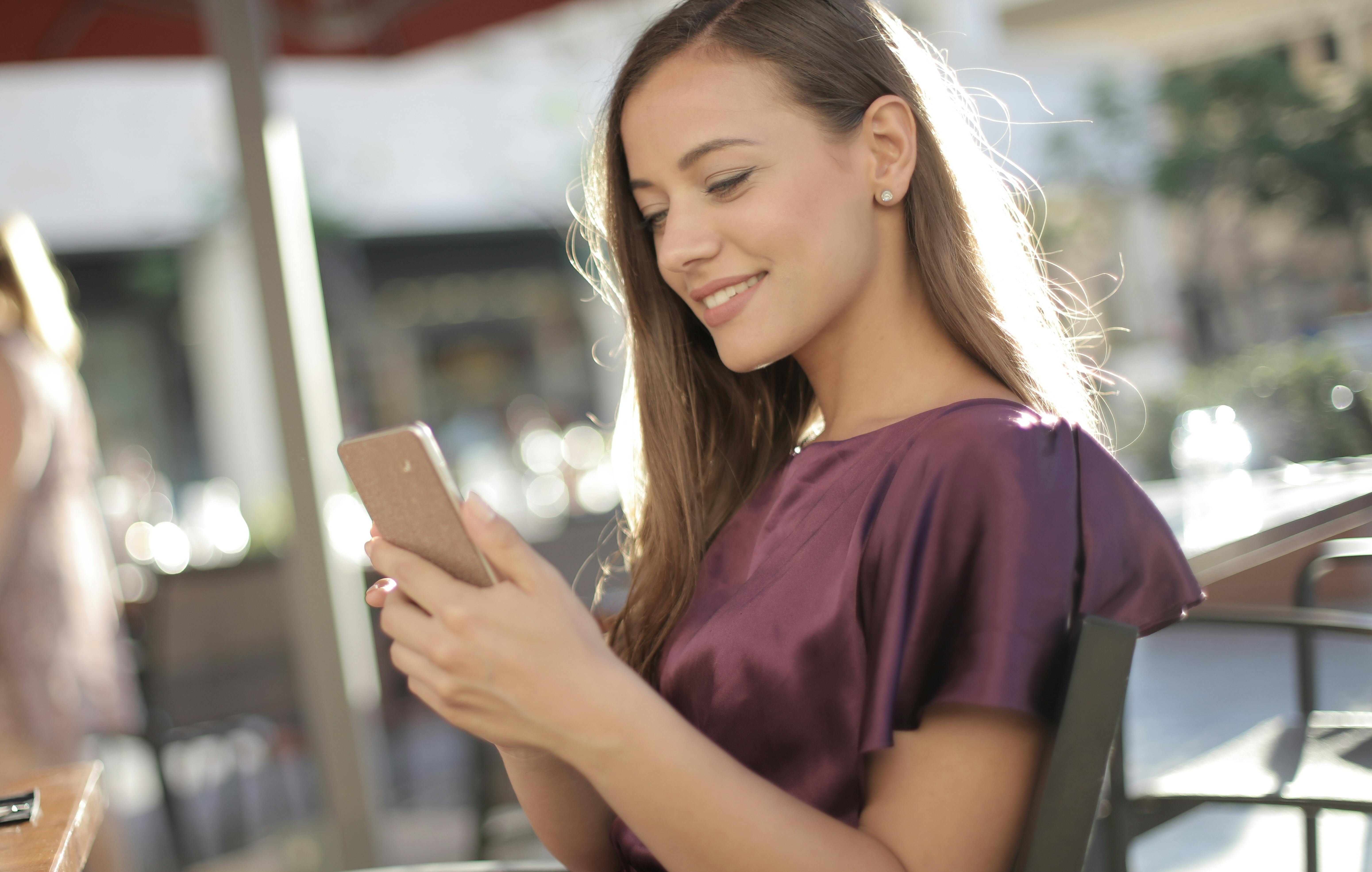 woman in purple shirt holding iphone