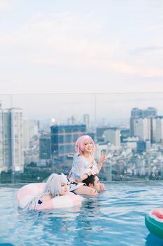 Two people in cosplay enjoy a rooftop pool with a city view, creating a vibrant and playful atmosphere.